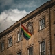 A rainbow pride flag flies on a pole in front of the Town Hall