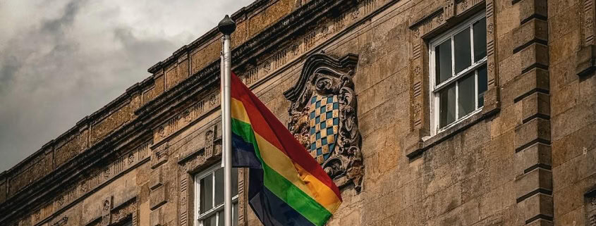 A rainbow pride flag flies on a pole in front of the Town Hall