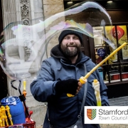 A market trader waves a large bubble wand in front of his market stand