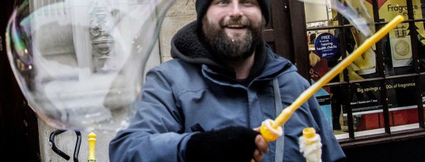 A market trader waves a large bubble wand in front of his market stand