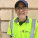 A man wearing glasses, a blue cap, and a high-visibility "Stamford Town Council" vest stands in front of a beige brick wall.